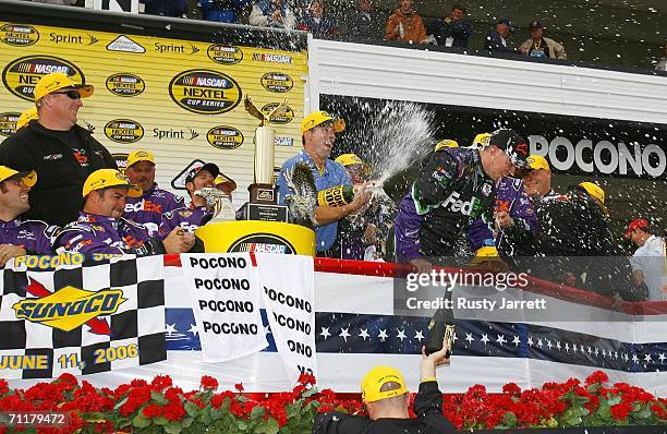 Owner JD Gibbs sprays Denny Hamlin, driver of the FedEx Ground Chevrolet, in Victory Lane after Hamlin's victory in the NASCAR Nextel Cup Series...