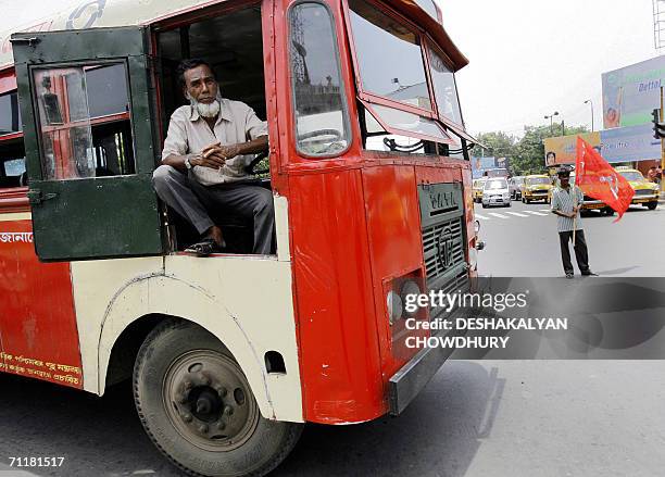 An Indian bus driver waits as Indian leftist activists holds party flags as they block a street during an observation of a five minutes 'chakka Jam'...