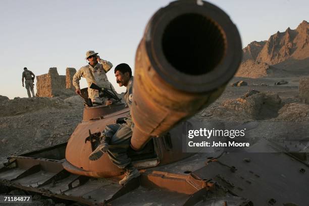 Army Col. Paul Calbos and Afghan police Maj. Gen. Dalut Zai Esmatollah sit atop a rusted Soviet tank overlooking Panjwai June 12, 2006 an area west...