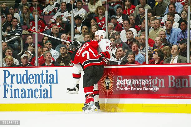 Brad Lukowich of the New Jersey Devils checks Cory Stillman of the Carolina Hurricanes along the boards in game three of the Eastern Conference...