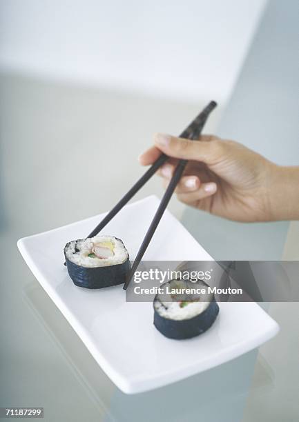 picking up sushi with chopsticks - sushis stock-fotos und bilder