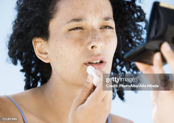 woman applying lip balm, holding compact - lip balm stock-fotos und bilder