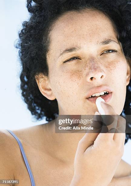 woman applying lip balm - lip balm stock-fotos und bilder