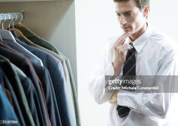 man choosing jacket from closet - professional wardrobe stock pictures, royalty-free photos & images