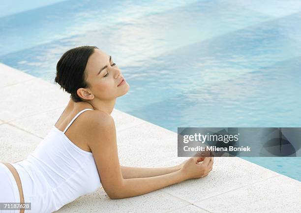 woman lying on ground by edge of pool, eyes closed - leaning on elbows stock pictures, royalty-free photos & images