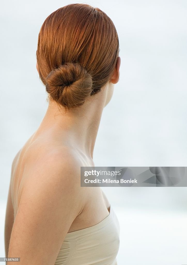 Woman with red hair in bun and strapless top, rear view