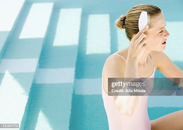 woman brushing hair by side of pool - summer hair bun stock pictures, royalty-free photos & images