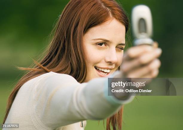 young woman holding up camera phone, taking photo - feature phone stockfoto's en -beelden