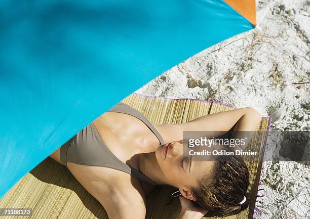 woman lying under parasol - beach mat stock pictures, royalty-free photos & images