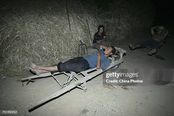 Villagers rest next to wheat straw at a threshing floor on June 12, 2006 in Lantian County of Shaanxi Province, China. China plans to increase its...