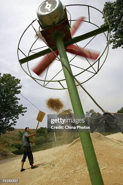 Villager winnows wheat at a threshing floor on June 12, 2006 in Lantian County of Shaanxi Province, China. China plans to increase its annual grain...