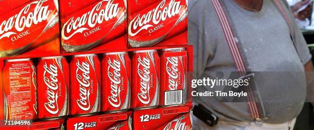 Heavyset man passes cartons of Coca-Cola displayed in a grocery June 13, 2006 in Des Plaines, Illinois. Doctors at the annual American Medical...