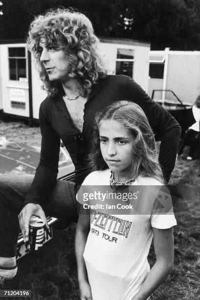 British singer Robert Plant of the rock and roll group Led Zeppelin stands, a can of 7UP soda in one hand, with his daughter Carmen Jane, who wears a...