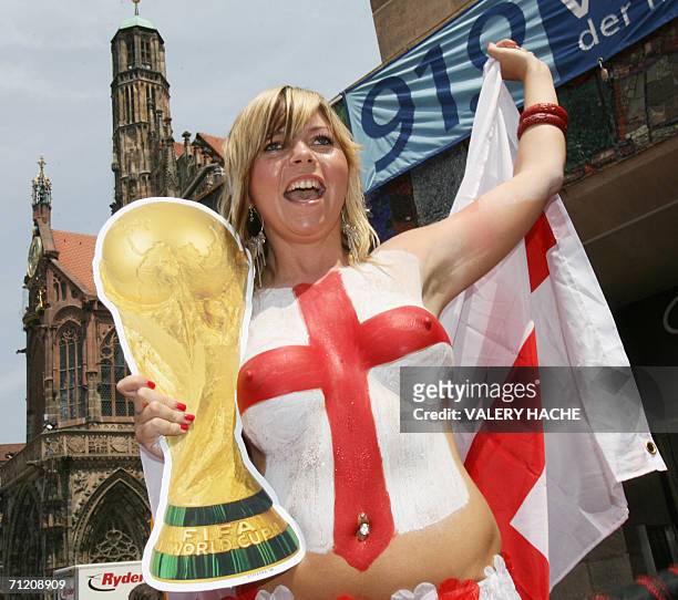 Female England supporter who has painted her naked bust with the colours of the St George's flag dances on a table of a cafe in the center of...