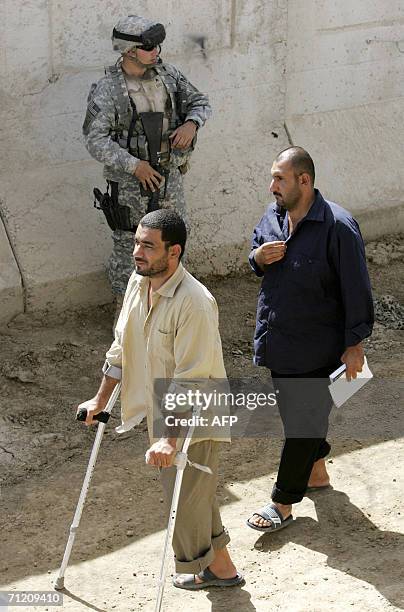 Iraqi prisoners walk past the U.S. Soldiers inside the Abu Ghraib prison compound, shortly before they are released, as another batch of 200...