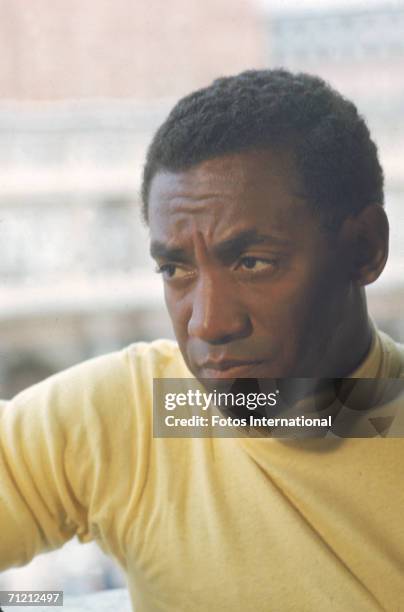 Portrait of American actor and comedian Bill Cosby, dressed in a yellow turtleneck, July 1966.