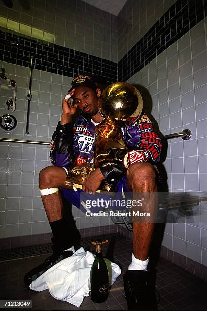 Kobe Bryant of the Los Angeles Lakers sits with the NBA Championship trophy after defeating the Philadelphia 76ers to win the 2001 NBA title on June...