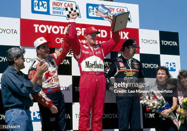 Nigel Mansell of Great Britain , Paul Tracy of Canada with the trophy and Bobby Rahal of the United States stand together on the victory podium...
