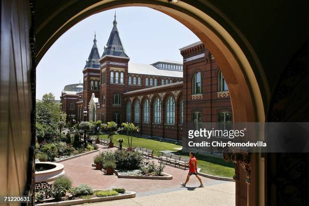 Tourists and visitors walk past the shuttered Smithsonian Institution Arts and Industries Building on the National Mall June 16, 2006 in Washington,...