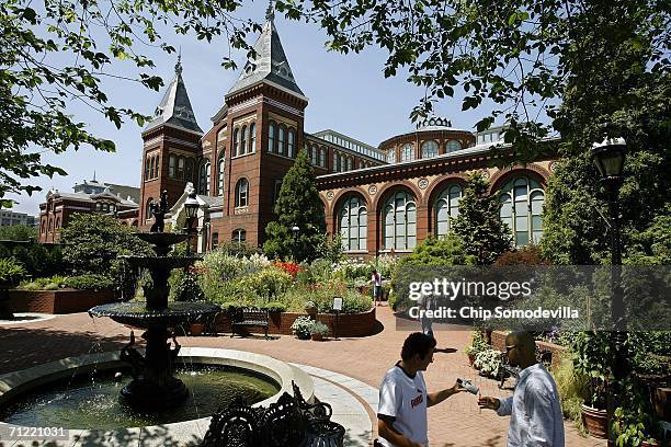 Tourists and visitors walk past the shuttered Smithsonian Institution Arts and Industries Building on the National Mall June 16, 2006 in Washington,...