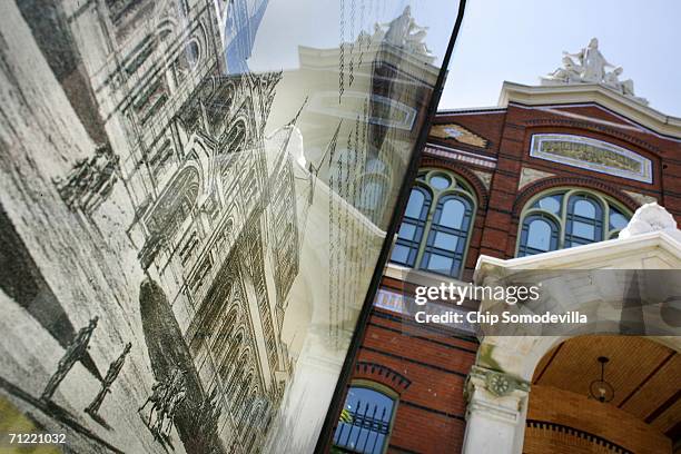 The Smithsonian Institution Arts and Industries Building is reflected in a sign displaying an antique drawing of the building on the National Mall...