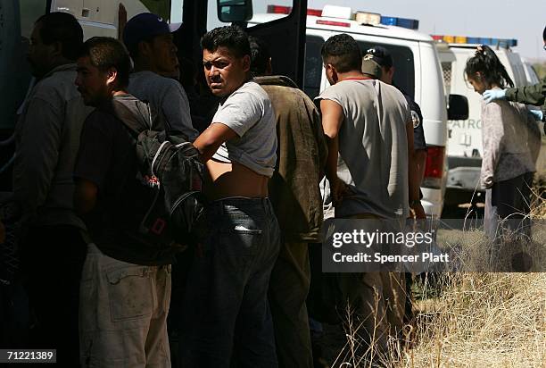 Men wait to be processed after being caught by U.S. Border Patrol agents after illegally crossing the border with Mexico June 16, 2006 in Pima...