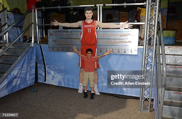 Young fan compares his arm span to that of NBA star Yao Ming at the NBA Rhythm 'N Rims Tour at the National Strawberry Festival on June 16, 2006 in...