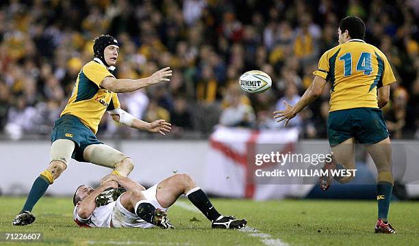 Australian flyhalf Stephen Larkham passes to teammate Mark Gerrard as he is tackled by England's George Chuter in the second Test Match against...