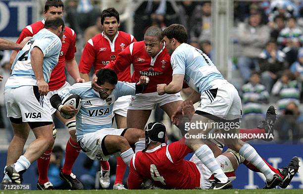 Buenos Aires, ARGENTINA: Argentina's Federico Todeschini is tackled by Wales' Ian Evans and teammate Gavin Thomas, next to Argentina's Mario Ledesma...