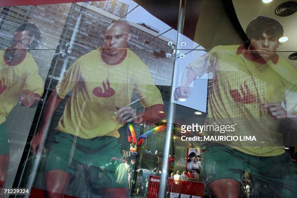 Revellers who dance atop of a sound truck decorated with rainbow baloons, are reflected on a bank window over an image of Brazilian soccer players...