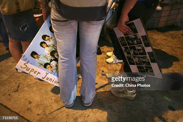 Fans hold posters and portraits of Korean singing group Super Junior to wait for their appearance at the opening ceremony of 9th Shanghai...