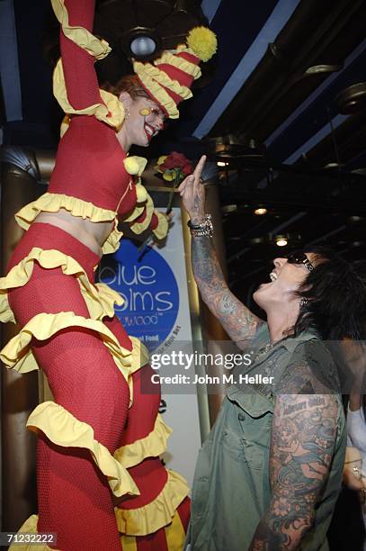 Nikki Sixx has some fun with one of clowns on stilts as he arrives at the 4th Annual Friends Of El Faro Fundraiser being held at the Music Box at the...