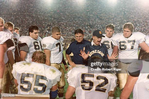 American college football coach Lou Holtz of Notre Dame guestures as the talks to his team on the sidelines in a packed stadium, late 1980s or early...