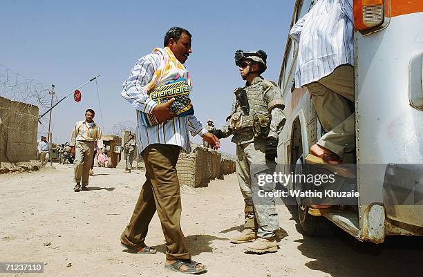 Solider stands guard as freed Iraqi prisoners get into a bus on June 19, 2006 at Abu Ghraib prison west of Baghdad, Iraq. More than 300 detainees...