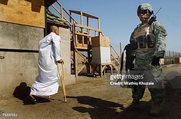 Solider stands guard as a freed Iraqi prisoner walks on June 19, 2006 at Abu Ghraib prison west of Baghdad, Iraq. More than 300 detainees were...