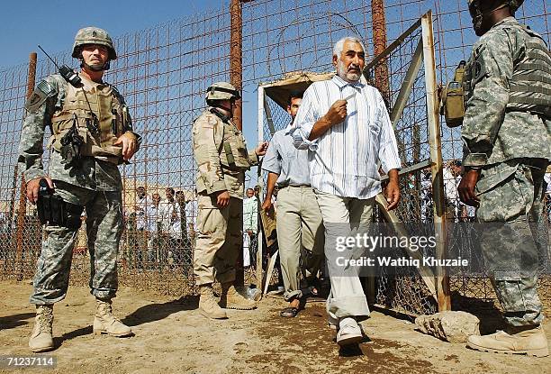 Soliders stand guard as freed Iraqi prisoners walk on June 19, 2006 at Abu Ghraib prison west of Baghdad, Iraq. More than 300 detainees were released...