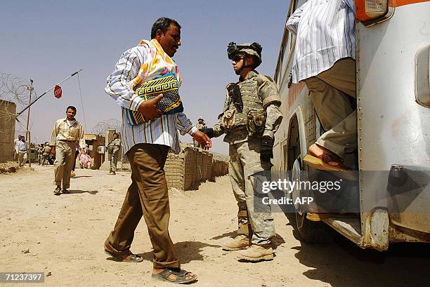 Solider stands guard freed Iraqi prisoners as they get into a bus 19 June 2006 at Abu Ghraib prison west of Baghdad, Iraq. Iraq released 500...