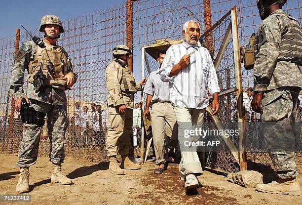 Soliders stand guard as freed Iraqi prisoners walk 19 June 2006 at Abu Ghraib prison west of Baghdad. Iraq released 500 detainees, the fourth batch...