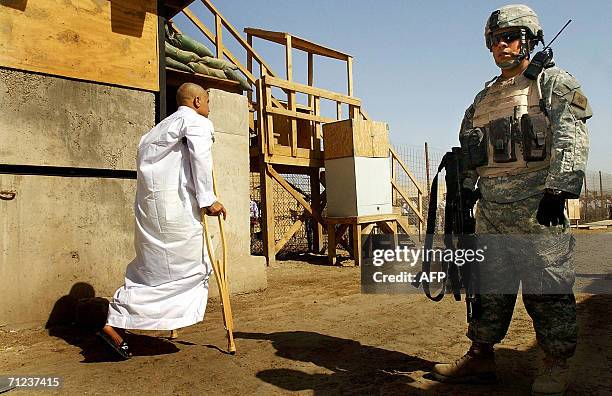 Solider stands guard as a freed Iraqi prisoner walks 19 June 2006 at Abu Ghraib prison west of Baghdad. Iraq released 500 detainees, the fourth batch...