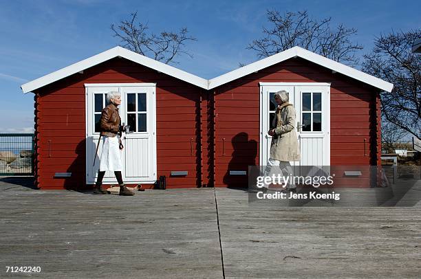 two mature women coming across in front of two huts - light coming through doors stock-fotos und bilder