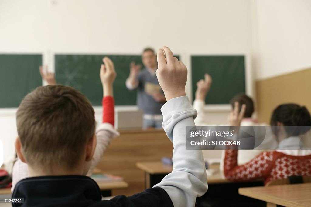 View inside a classroom, pupils raising arms