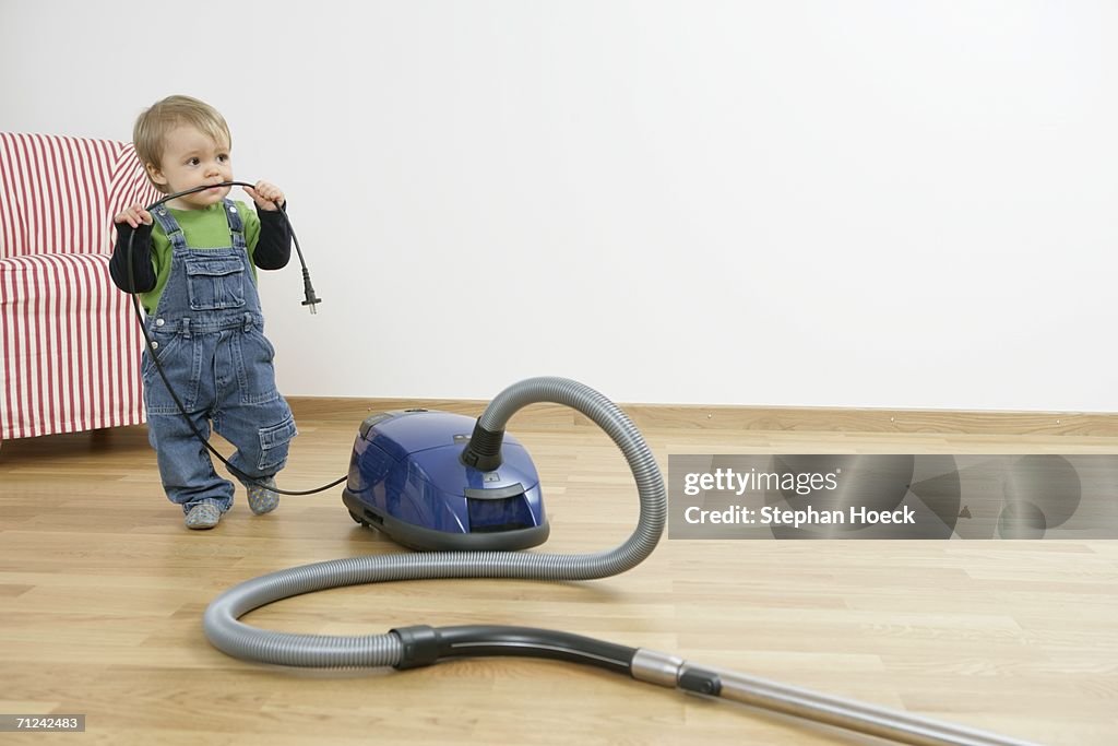 Baby boy with vacuum cleaner cable in the mouth