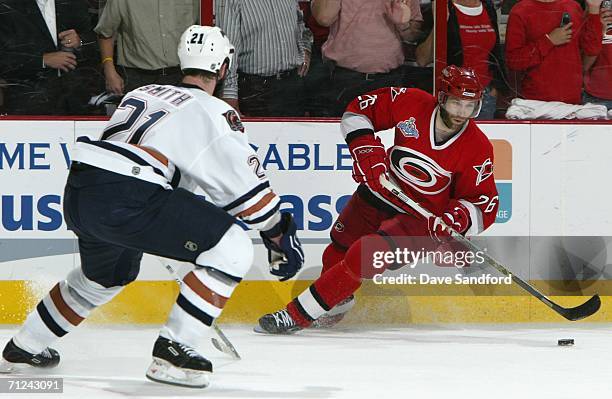 Erik Cole of the Carolina Hurricanes skates with the puck under pressure from Jason Smith of the Edmonton Oilers during game seven of the 2006 NHL...