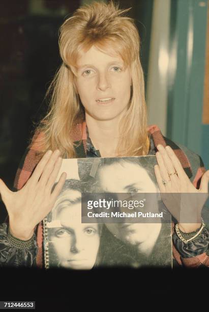 American photographer and musician with rock group Wings, Linda McCartney pictured holding a spiral bound book with a cover image featuring a...
