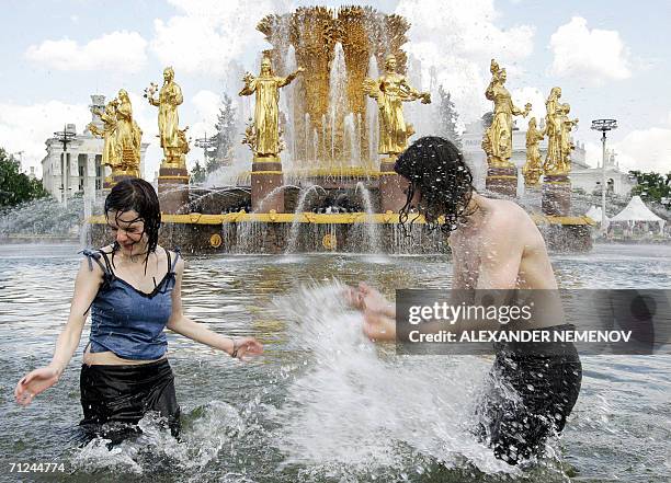 Moscow, RUSSIAN FEDERATION: Two teenagers cool themselves, as temperatures soared over 30 degrees Celsius, in a fountain representative of the...