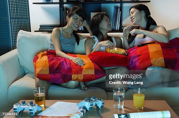three young women in living room, sitting on sofa - coffee table front view stock pictures, royalty-free photos & images