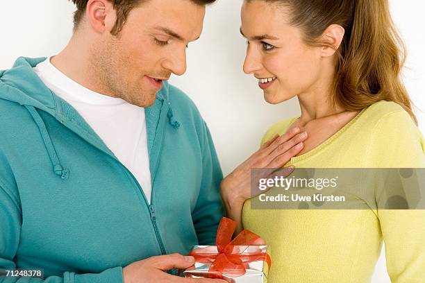 man giving gift to woman, smiling, close-up - 2 jeunes timide fond blanc photos et images de collection