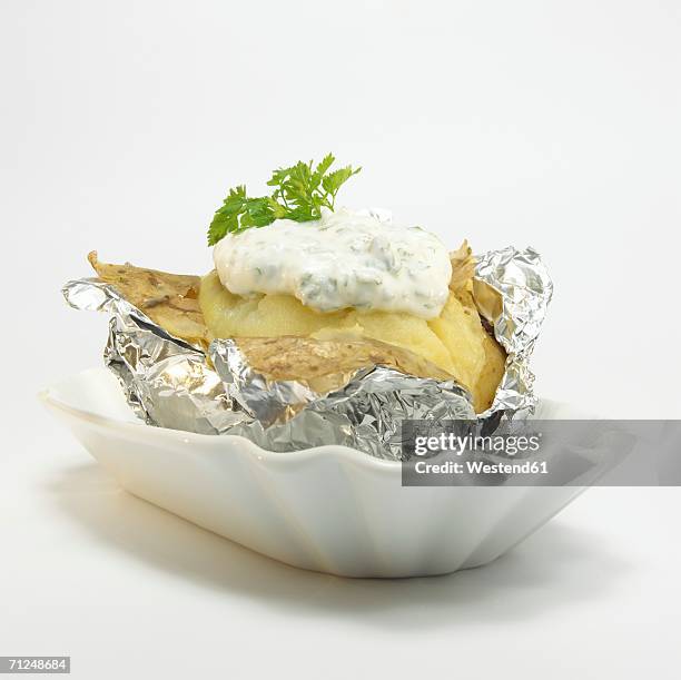 baked potato with curd cheese in foil, close-up - gebackene kartoffel stock-fotos und bilder