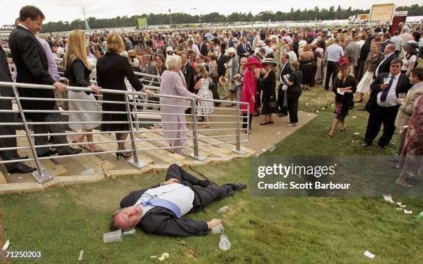 Man lies on the ground as race-goers walk past him on the first day of Royal Ascot, at the Ascot Racecourse on June 20, 2006 in Ascot, England. The...