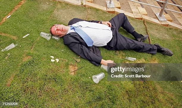 Man lies on the ground as race-goers walk past him on the first day of Royal Ascot, at the Ascot Racecourse on June 20, 2006 in Ascot, England. The...